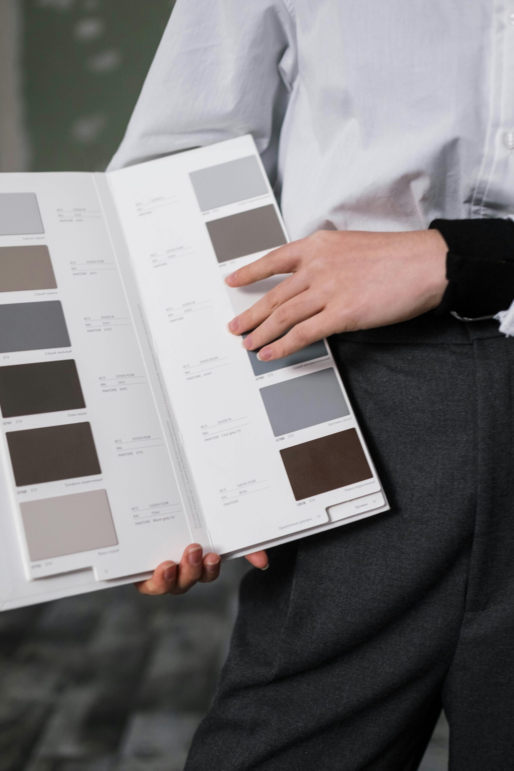 Close-up of a person holding a color swatch palette indoors, displaying various shades.